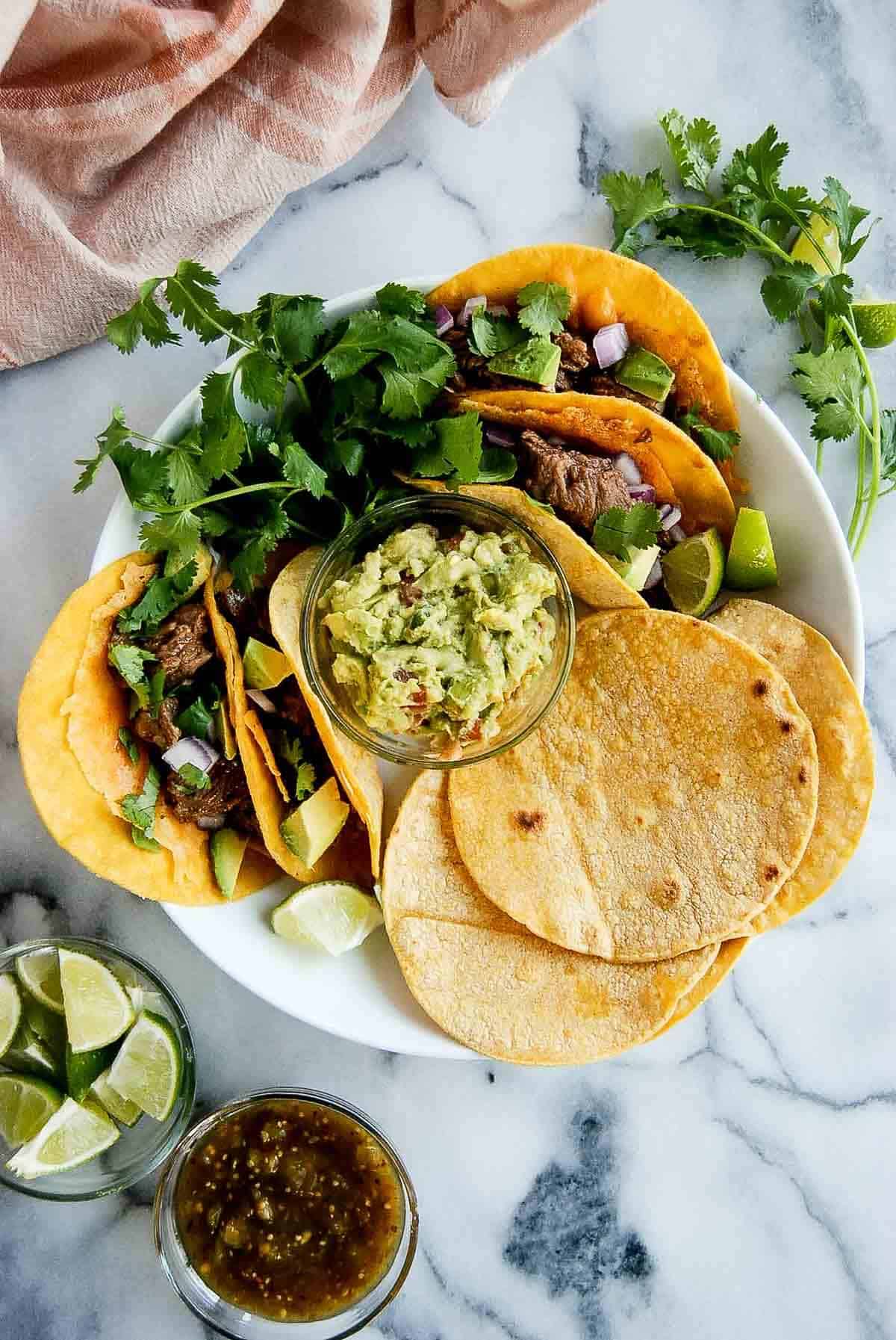 carne asada vampiro tacos on plate with extra tortillas.