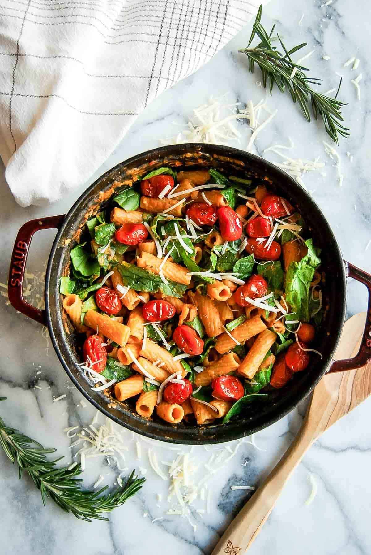 pasta with chickpeas, spinach and fresh tomatoes in pot on countertop.