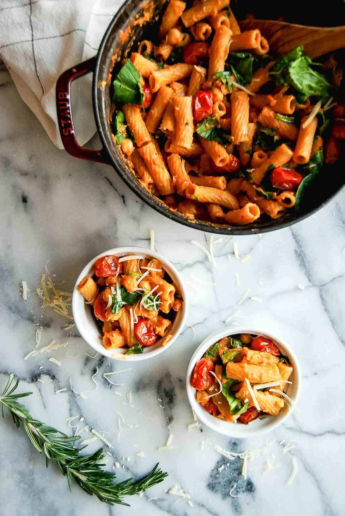 small serving bowls with pasta e ceci on countertop, with larger serving dish to the side.