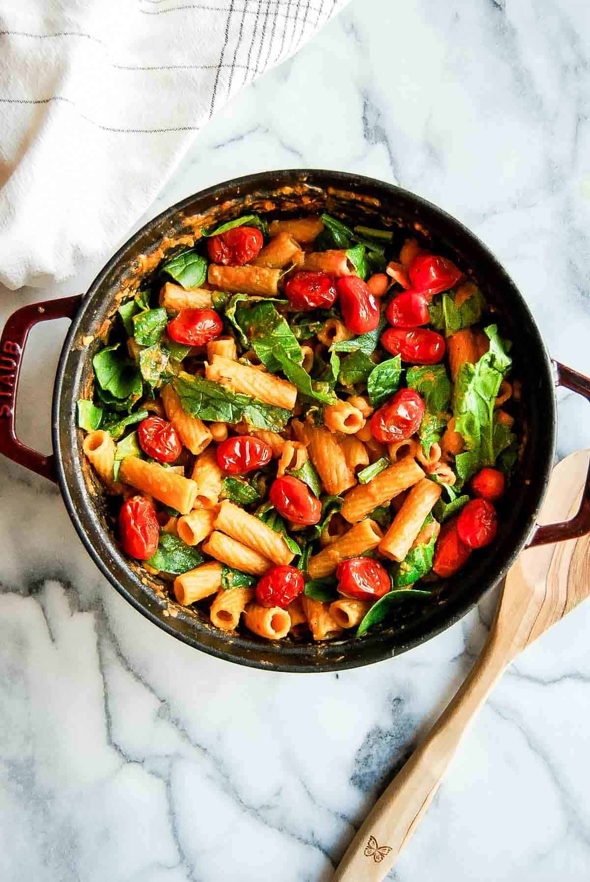 pasta with chickpeas, spinach and tomatoes in pot on countertop.