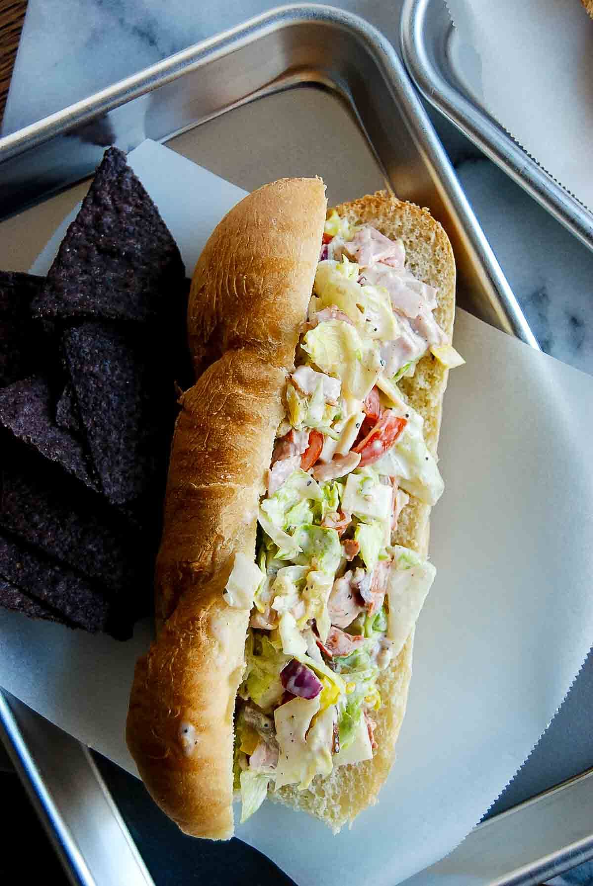 italian chopped sandwich on tray with chips.