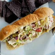 grinder salad sandwich on tray with chips.