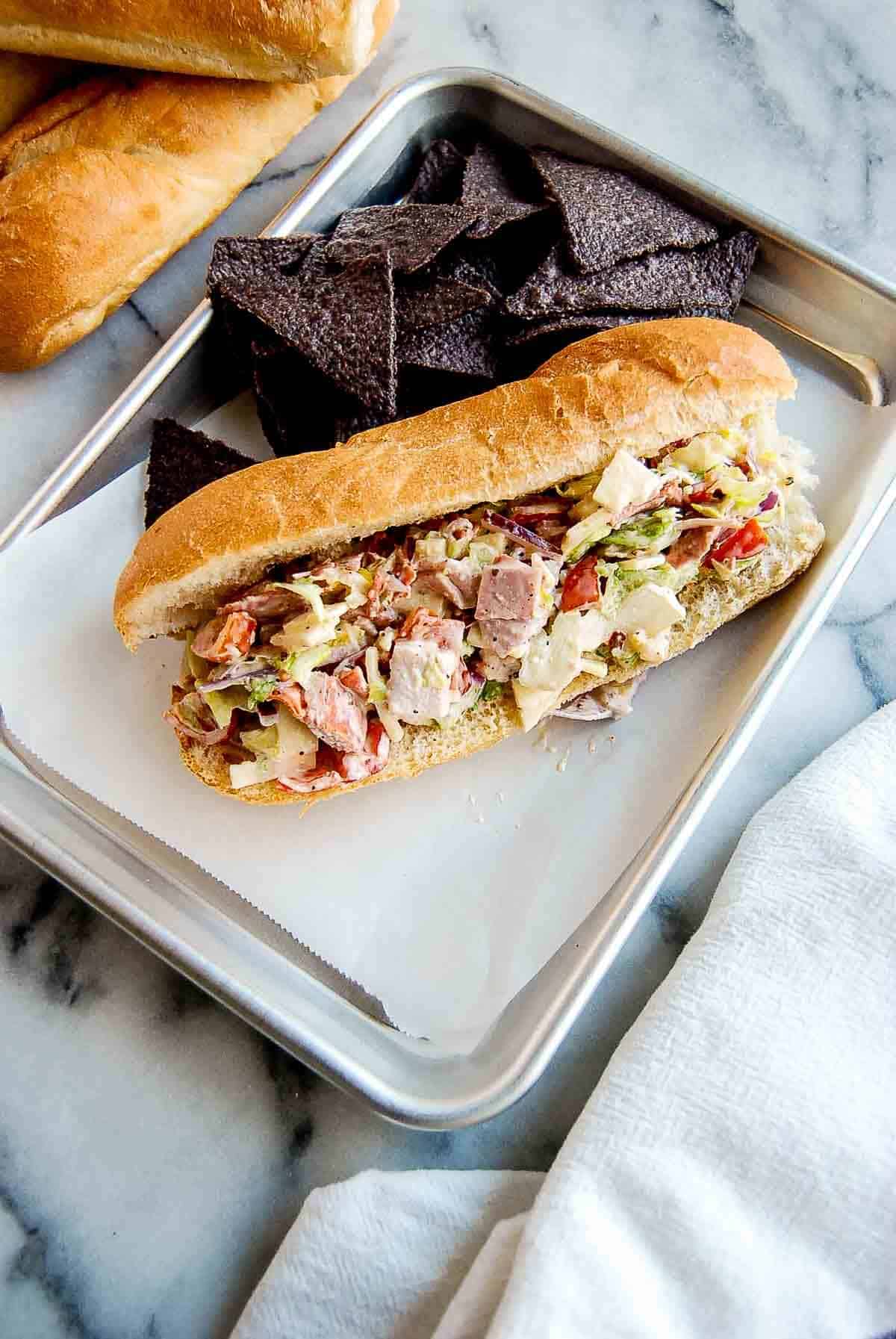 chopped italian sandwich on tray with chips.