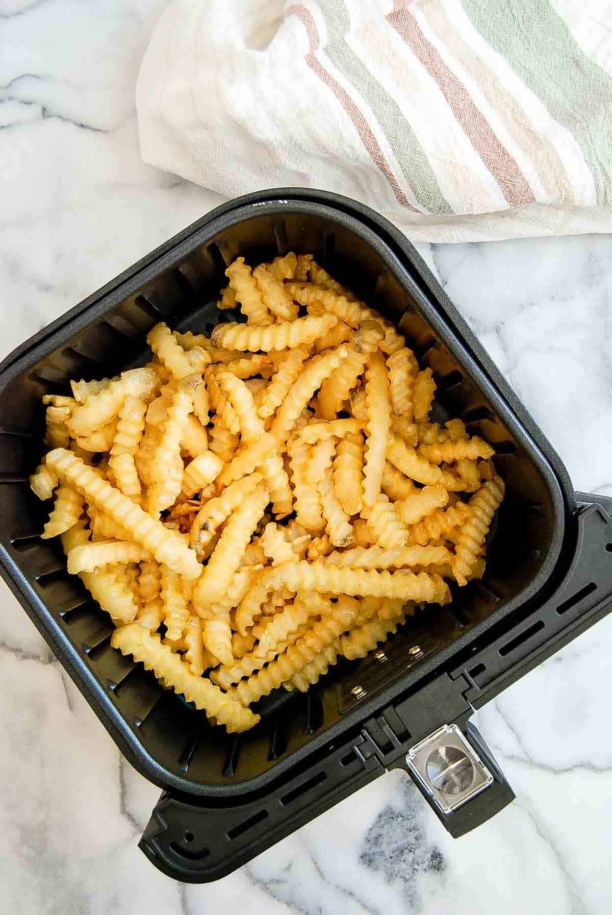 frozen french fries in air fryer basket.