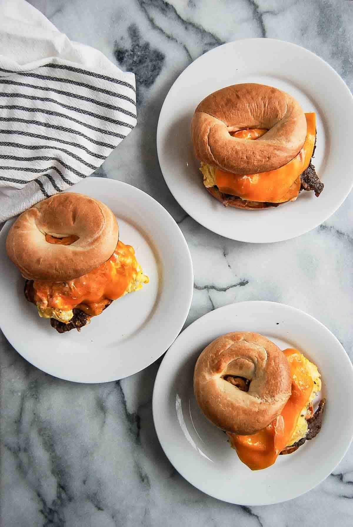 Steak, egg and cheese bagels on plates.