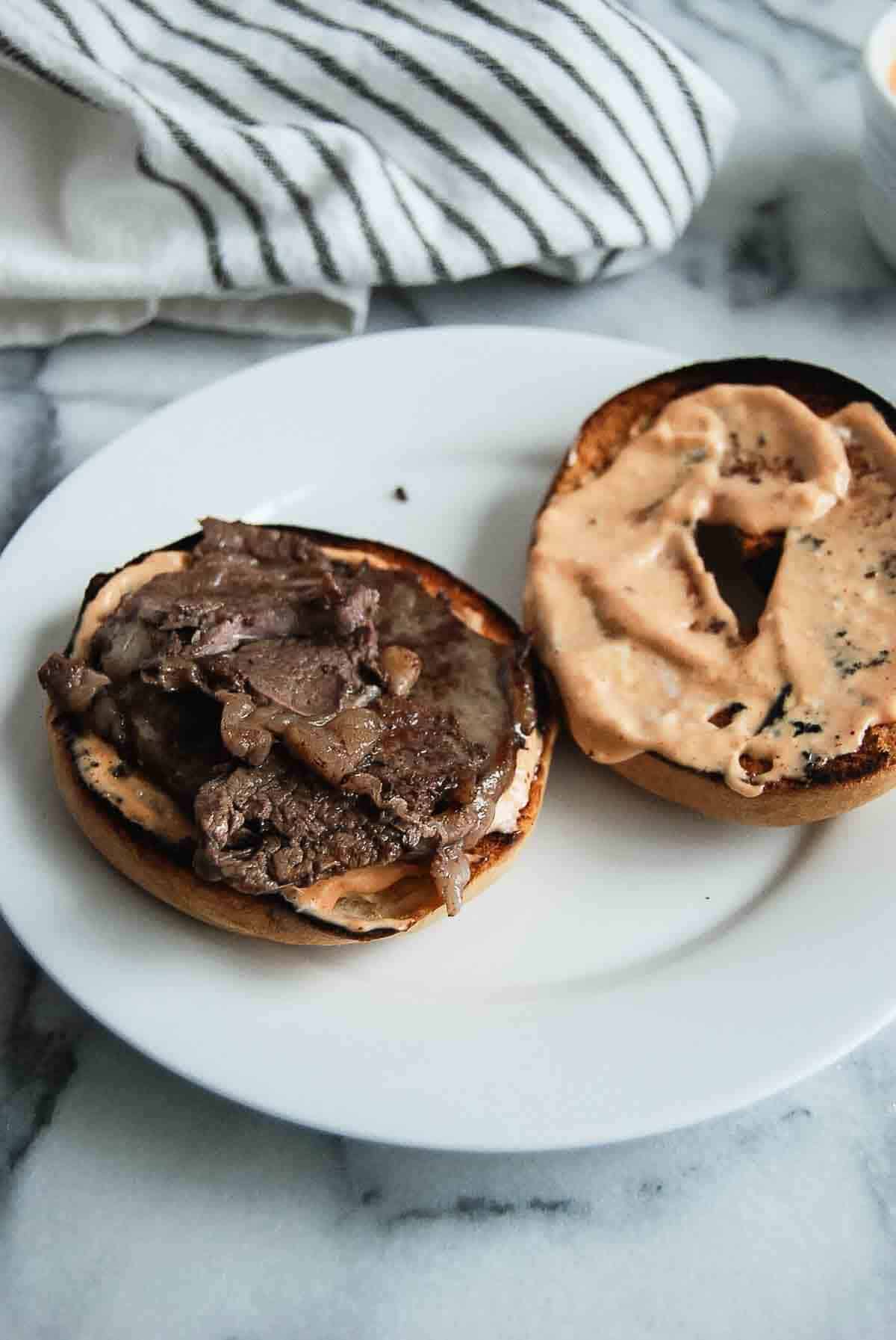 Bagel with breakfast sauce topped with ribeye steak.