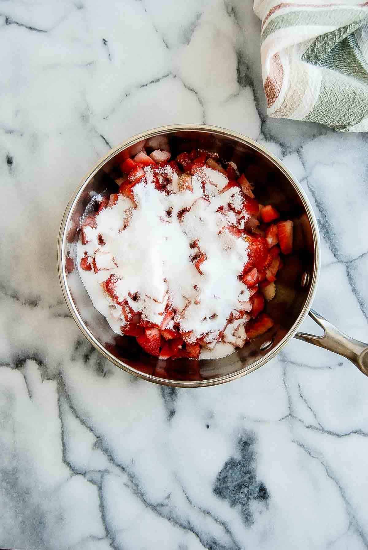 diced strawberries with sugar and lemon juice in saucepan.