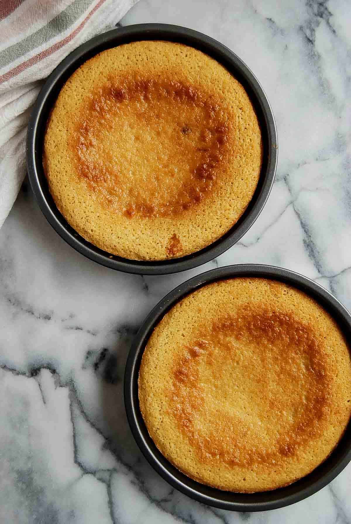 two round, cooked vanilla cakes in pans.