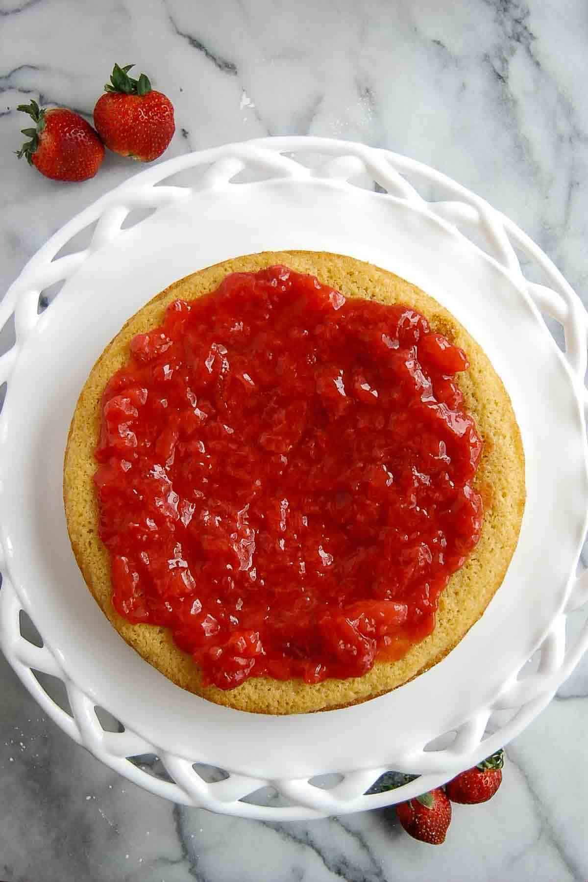 layer of vanilla cake with strawberry cake filling spread on top.