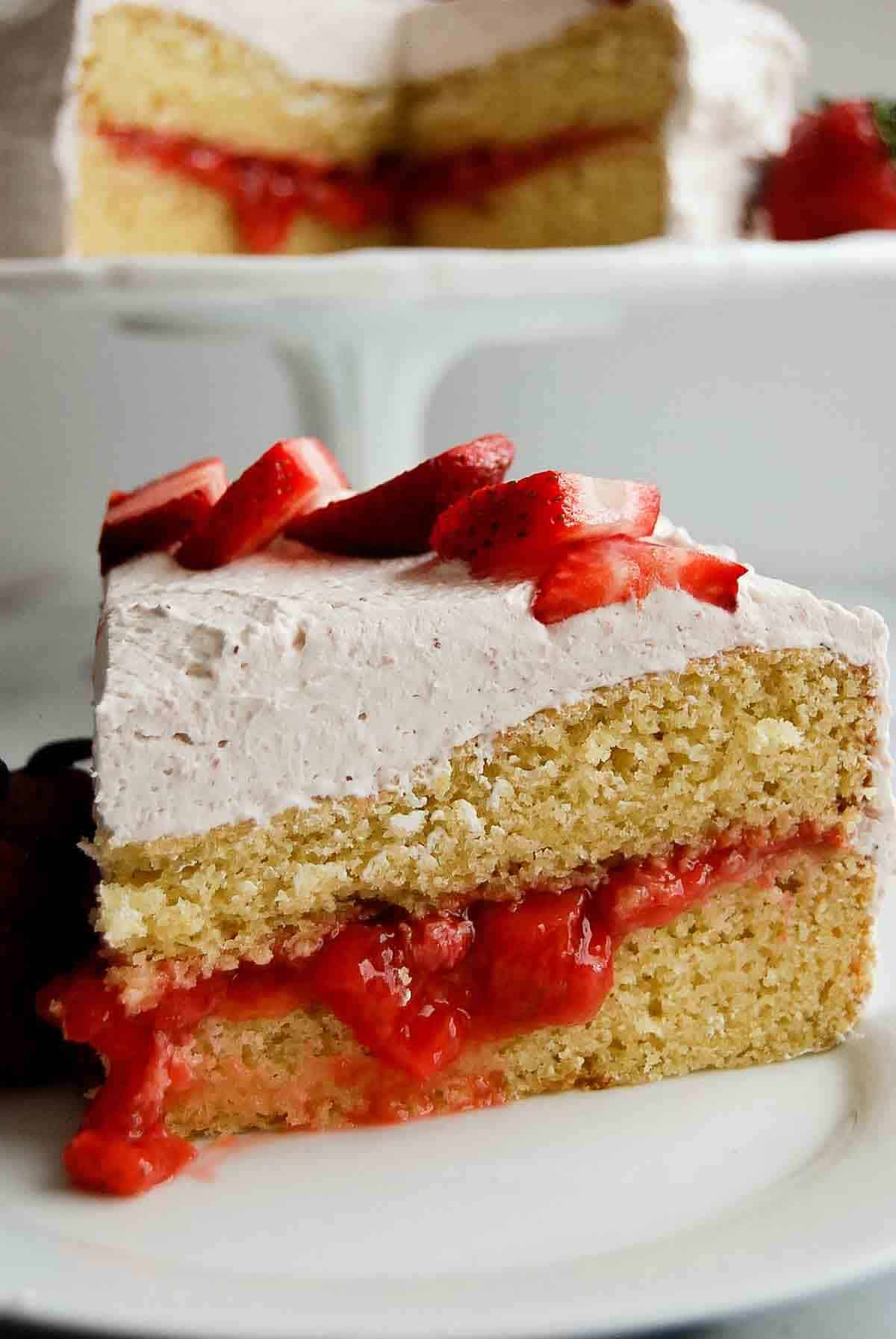 closeup of strawberry vanilla cake with strawberry cake filling in the middle and iced with strawberry whipped cream.