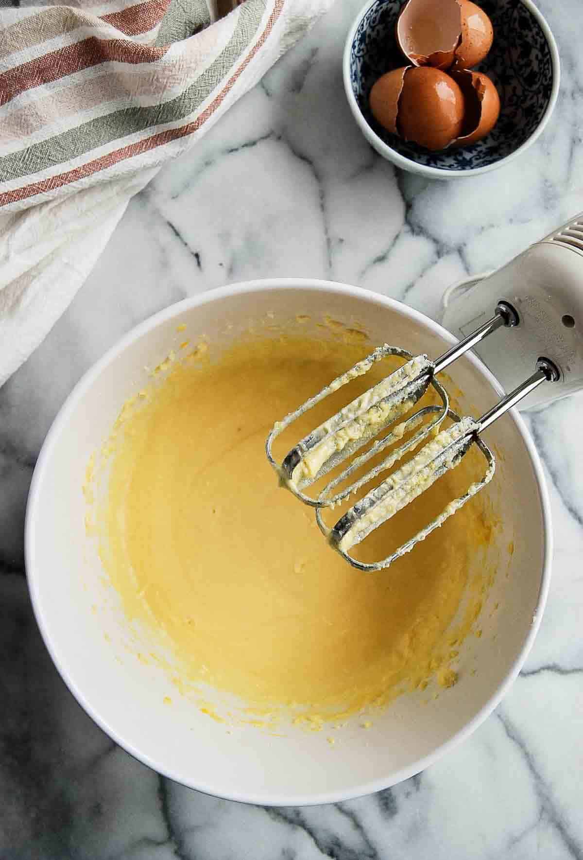 creamed butter and sugar in bowl with hand mixer on the side.