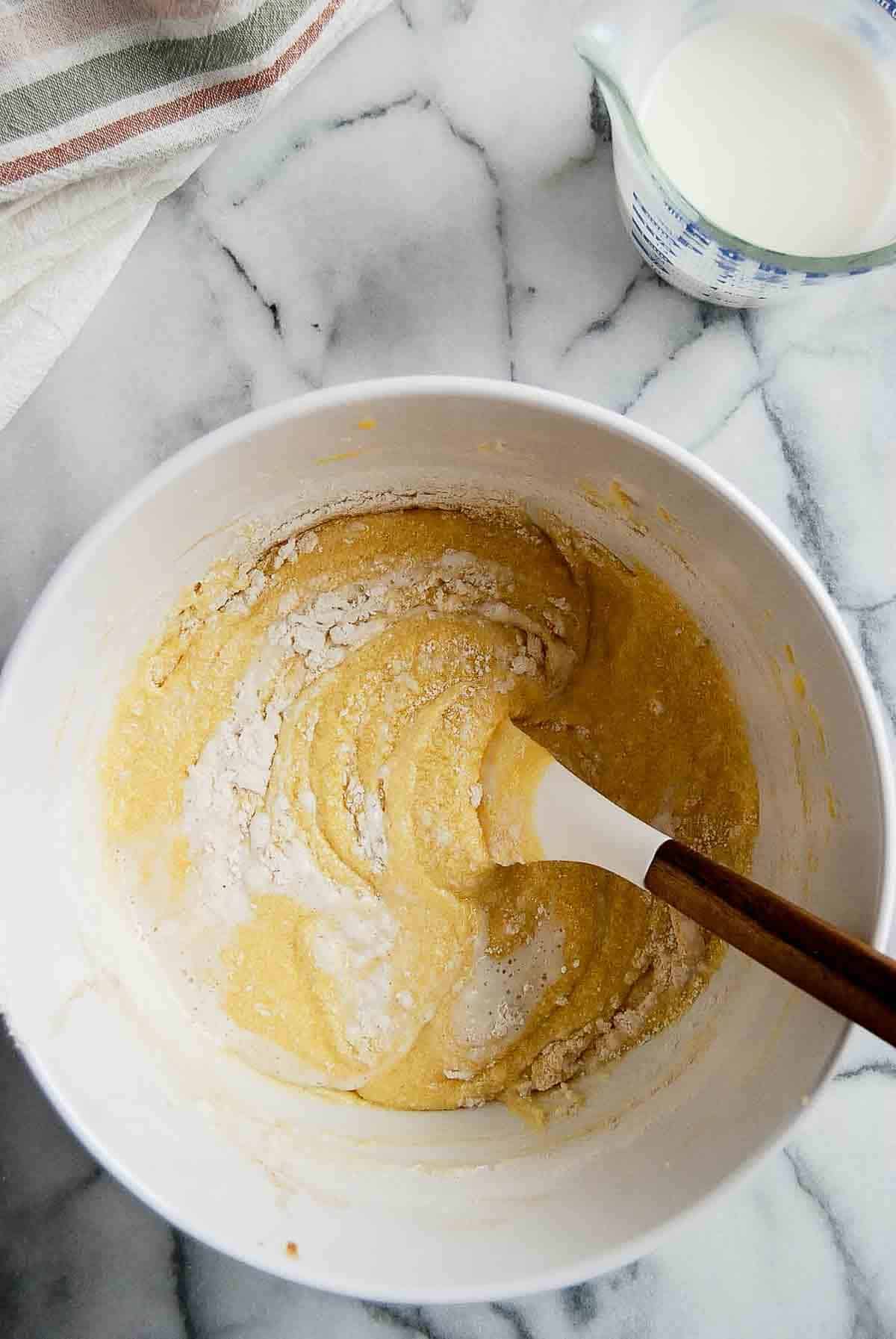 mixing wet and dry ingredients of vanilla cake batter in bowl.