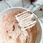 strawberry whipped cream in bowl with hand mixer to the side.