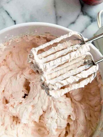 strawberry whipped cream in bowl with hand mixer to the side.