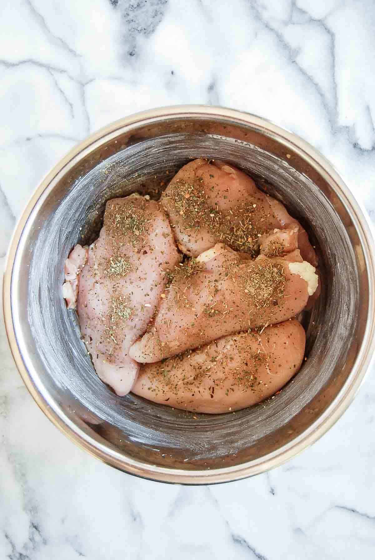 chicken breast in crockpot with seasonings.