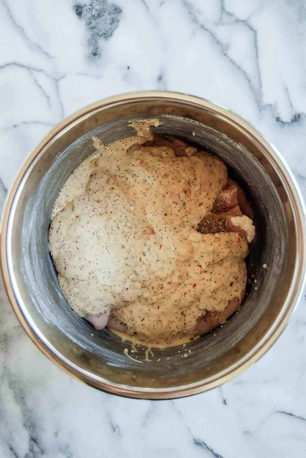 chicken breast in crock pot with garlic parmesan sauce poured over the top.