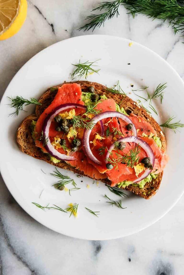 smoked salmon toast with avocado, capers, dill, lemon zest, and red onion.