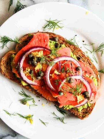 smoked salmon toast with avocado on plate.