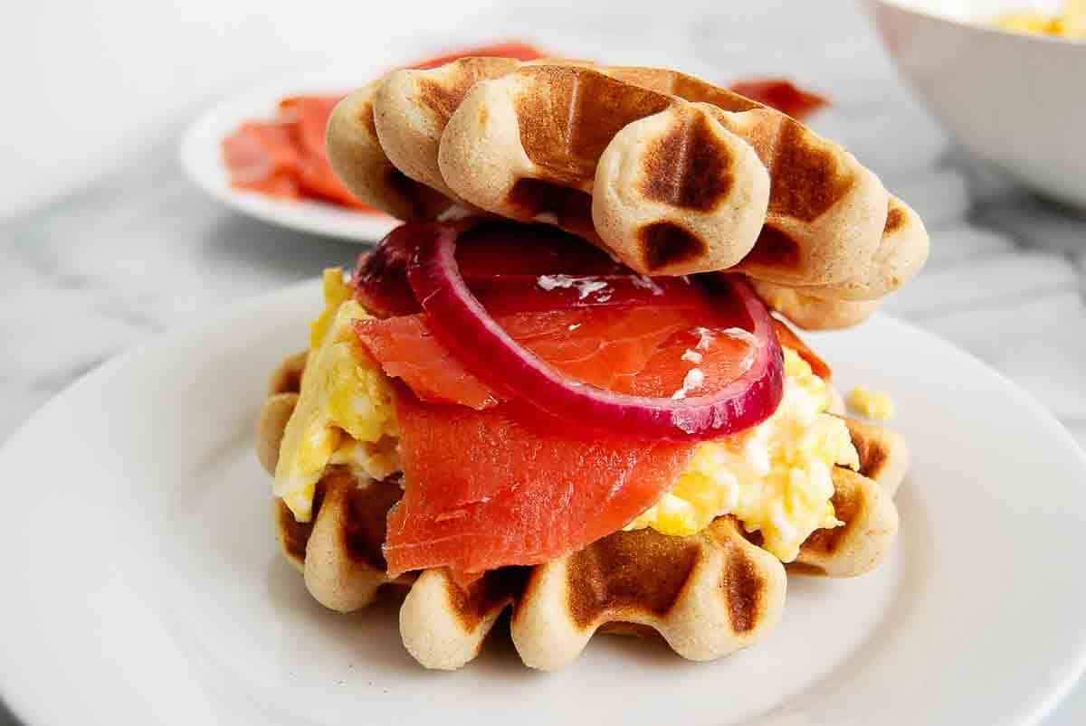 closeup of waffle breakfast sandwich on plate.