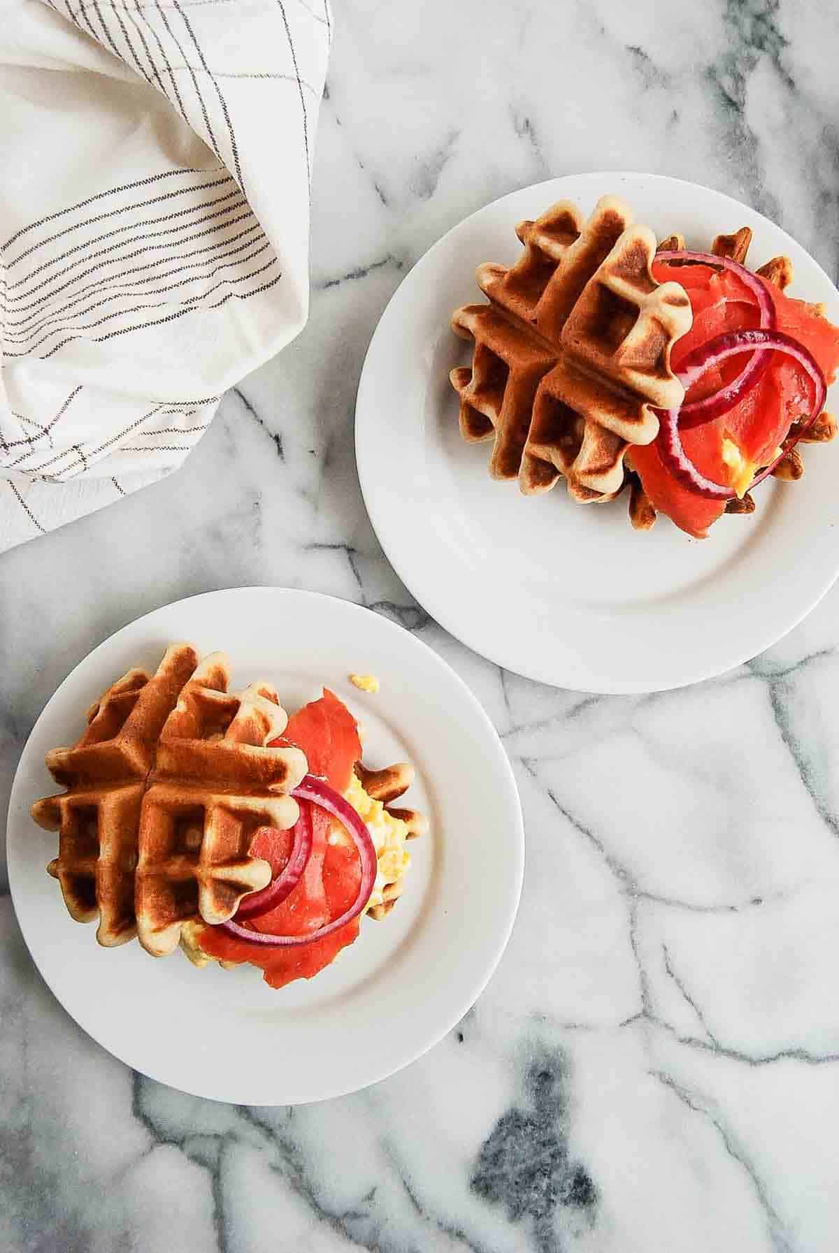 waffle breakfast sandwiches on plates, sitting on countertop.