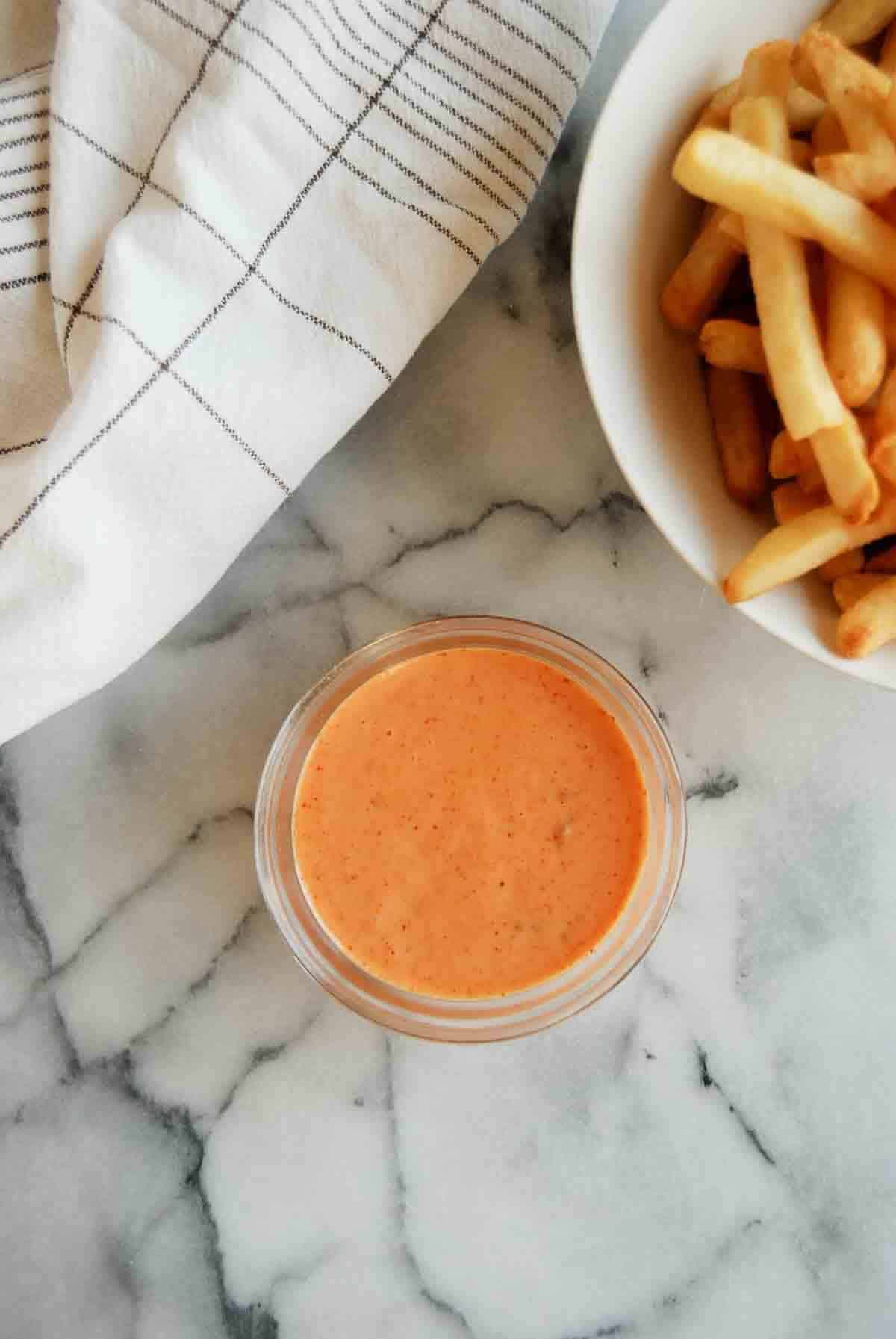 closeup of boom boom sauce with bowl of fries on the side.