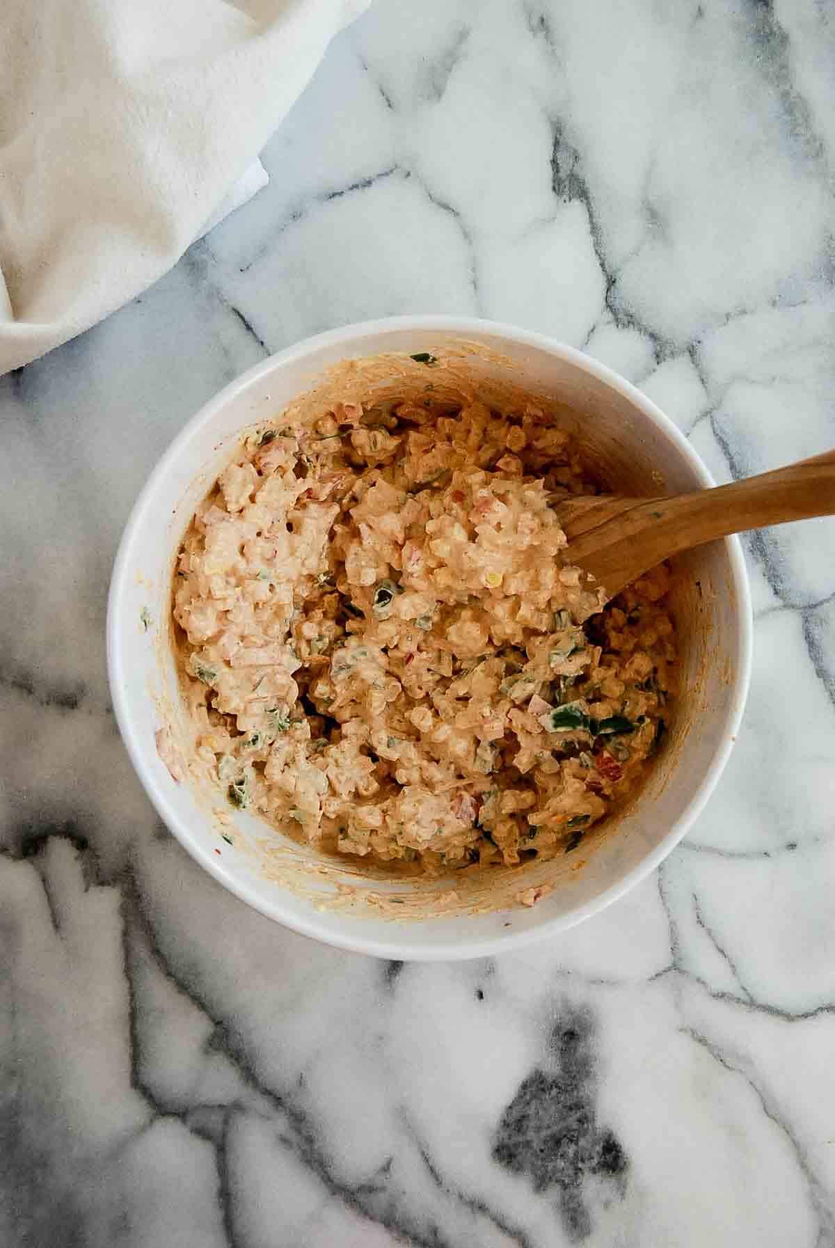 cream cheese, spices, corn and veggies mixed in a bowl.