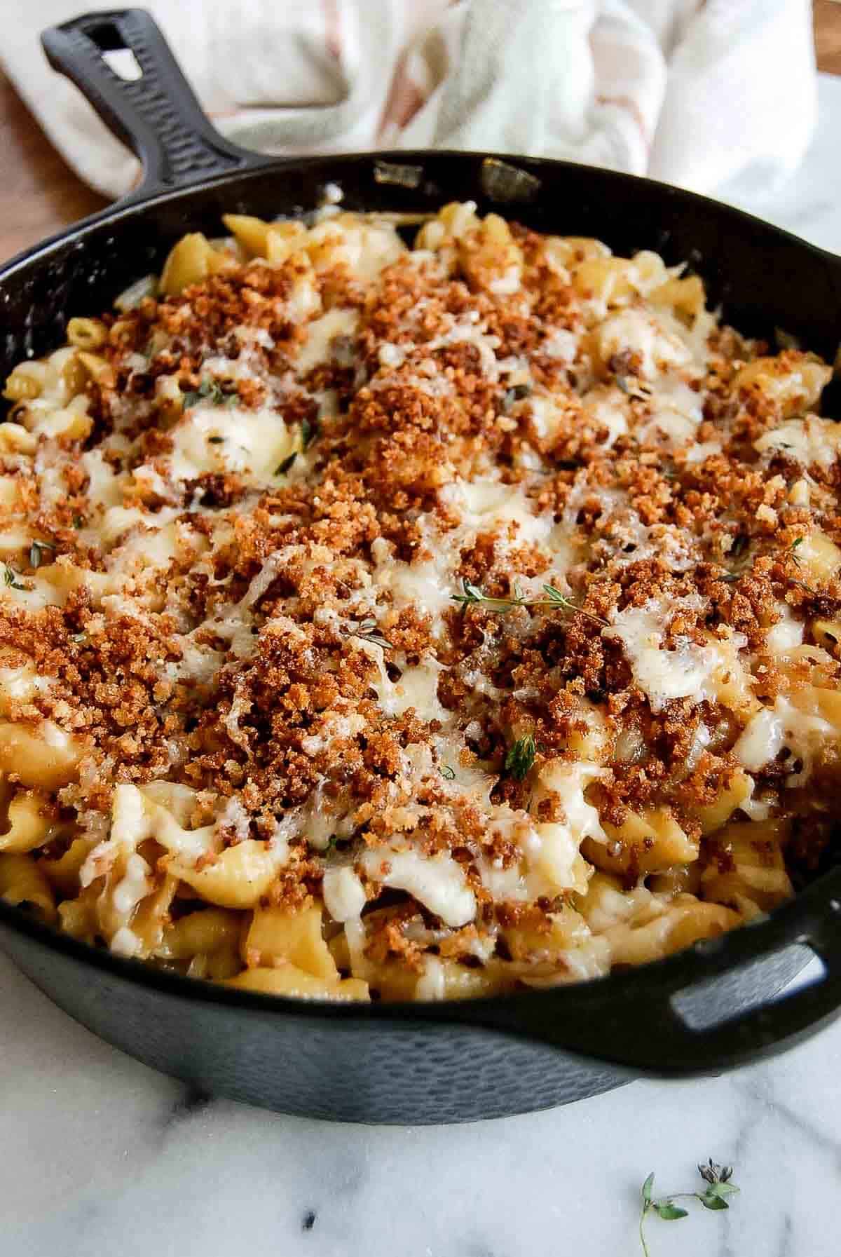 side view of skillet of french onion soup pasta with toasted breadcrumbs on top.