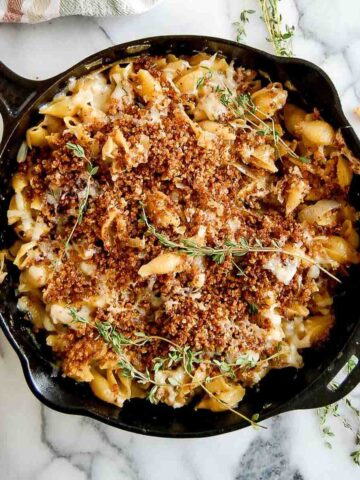 skillet of french onion soup pasta with toasted breadcrumbs and thyme on top.