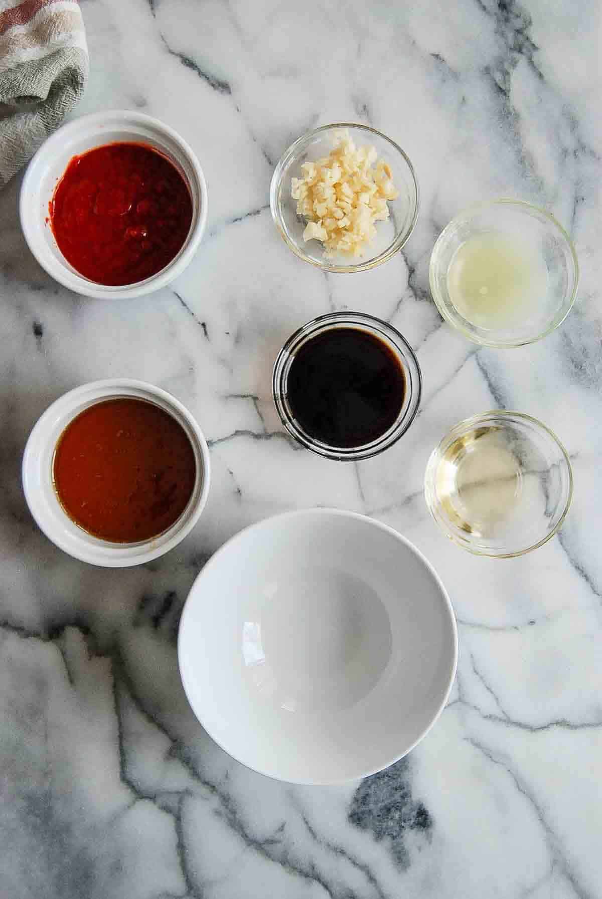 ingredients for honey sriracha sauce ready to be mixed, in bowls on countertop.