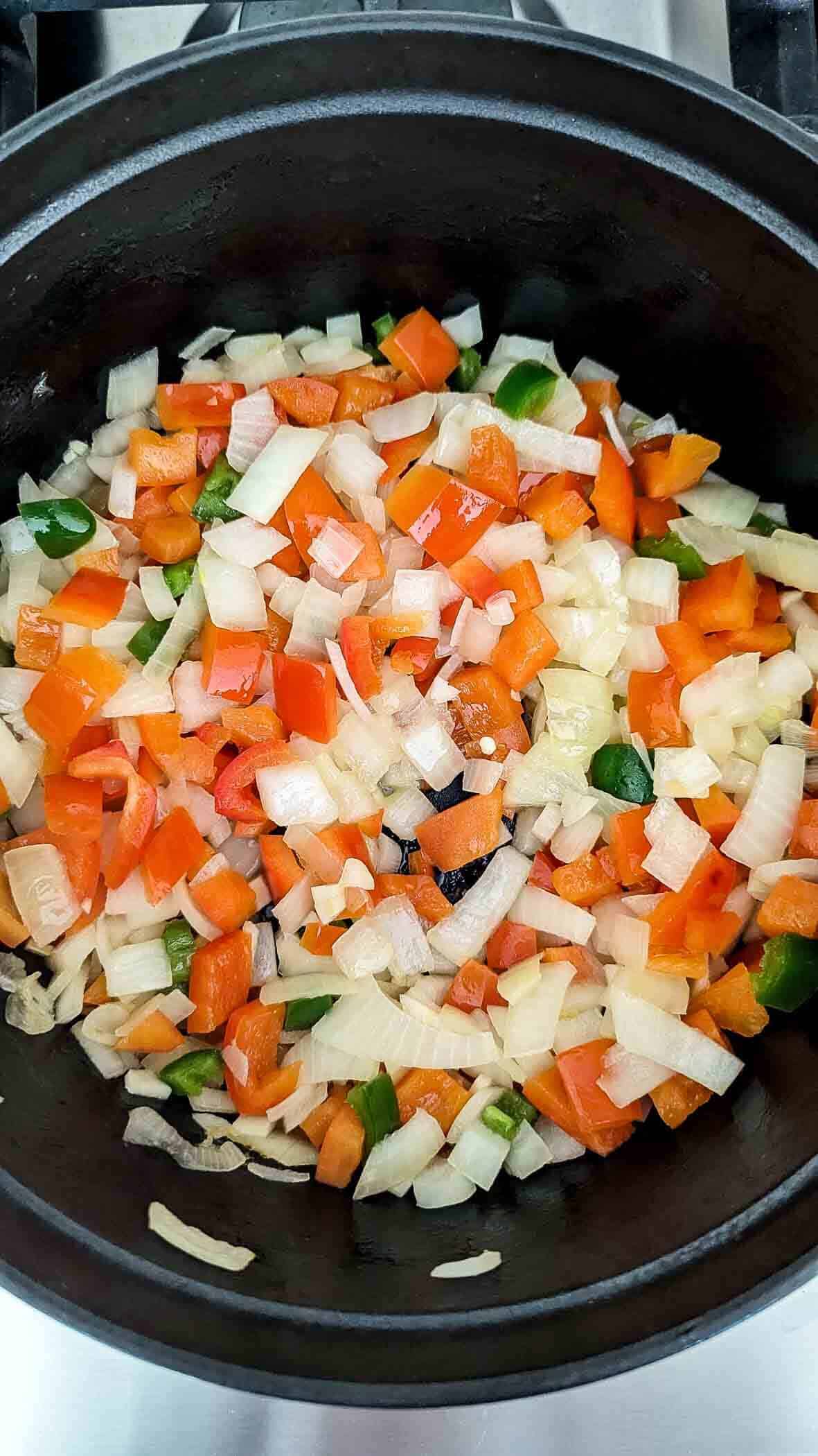 onions, bell peppers and jalapenos sauteeing in dutch oven.