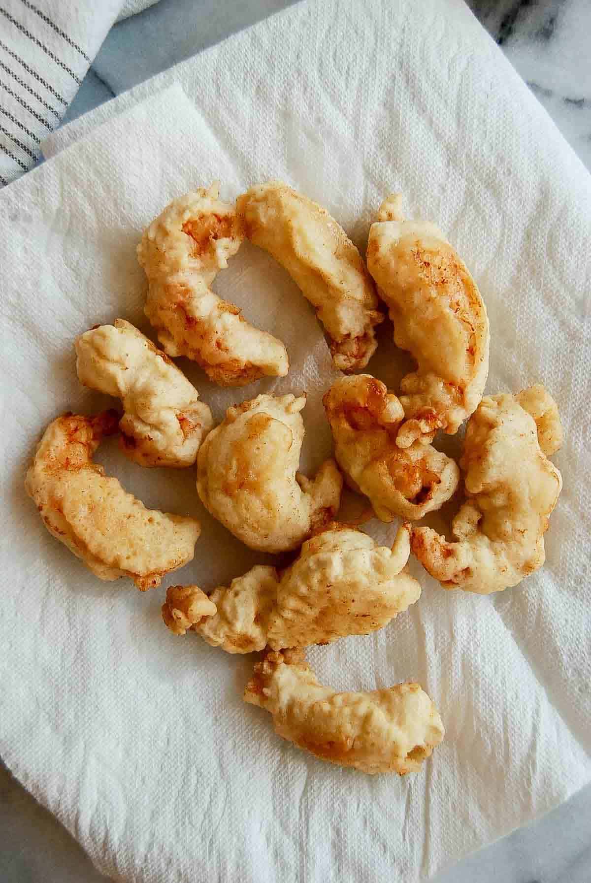 tempura shrimp on paper towel lined plate.