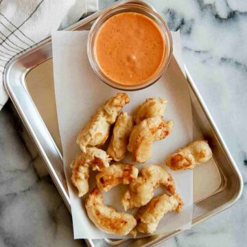 tempura shrimp on tray with dipping sauce on the side.