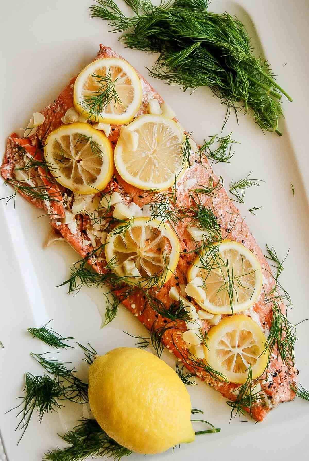 oven baked salmon with lemon and dill on serving platter.