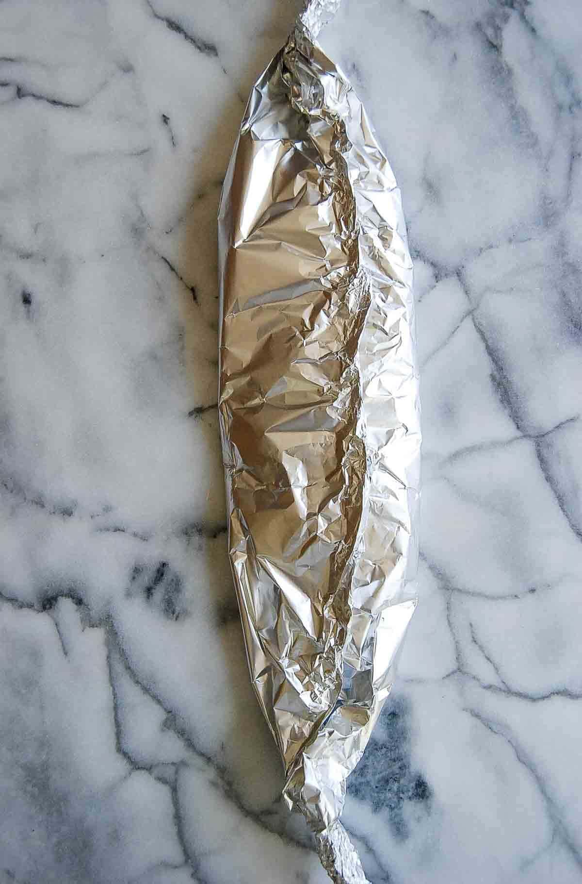 foil packet with salmon, lemon and dill inside.