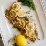 baked salmon with lemon and dill on serving platter.