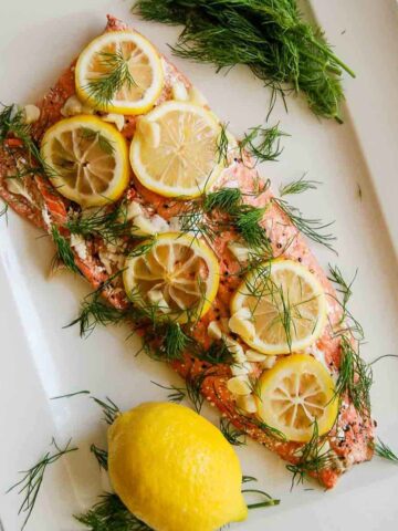 baked salmon with lemon and dill on serving platter.