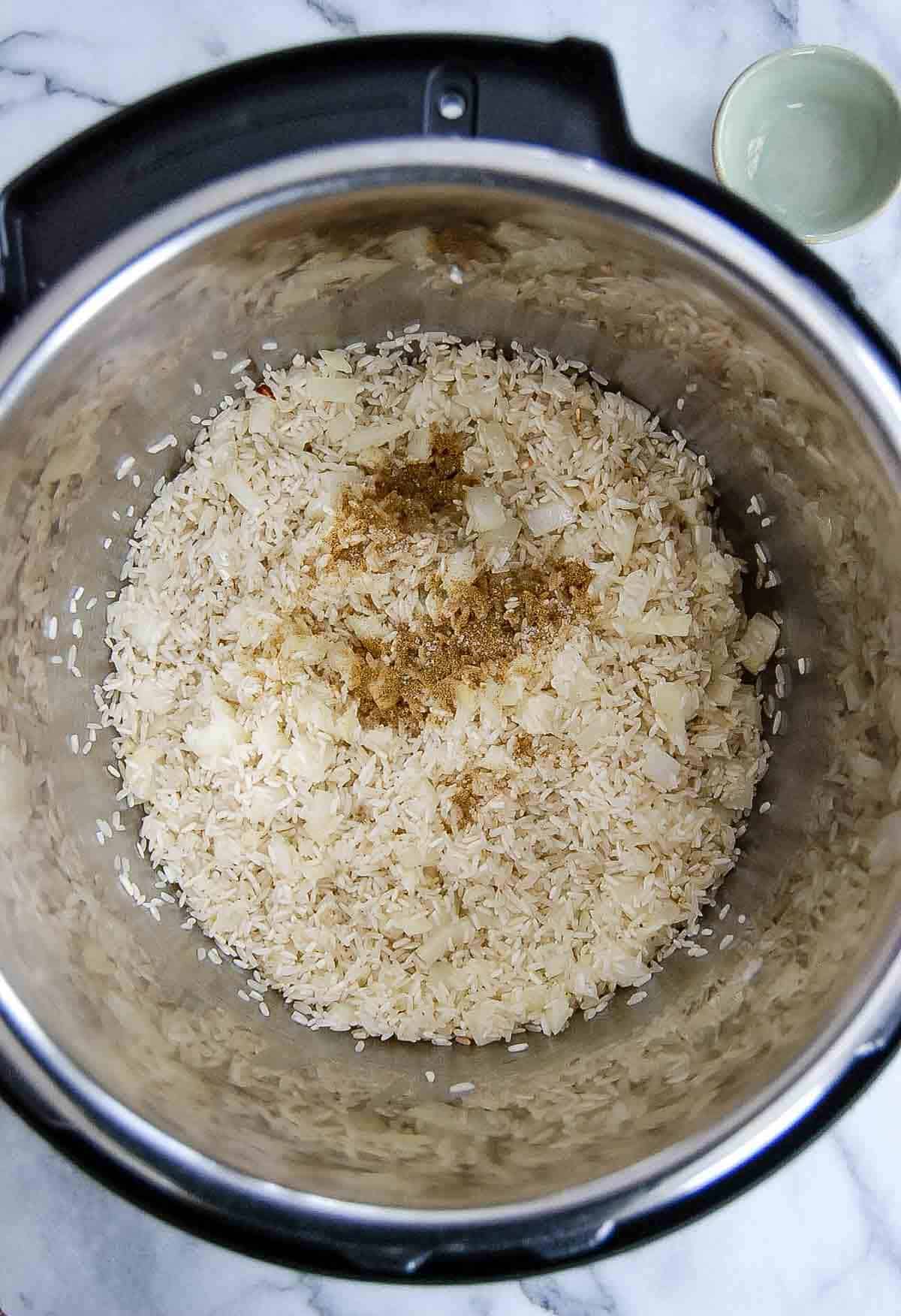 rice, spices and onions in pressure cooker.