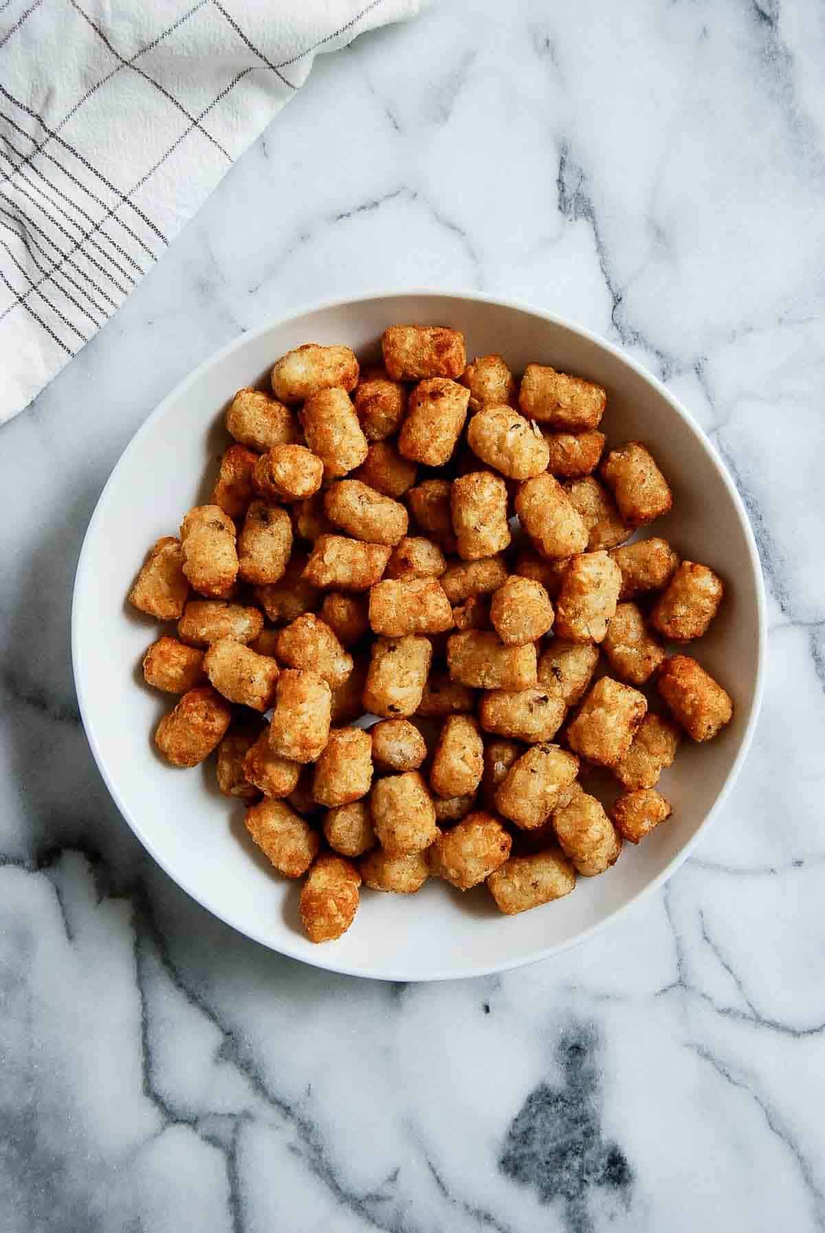 baked tater tots in bowl on countertop.