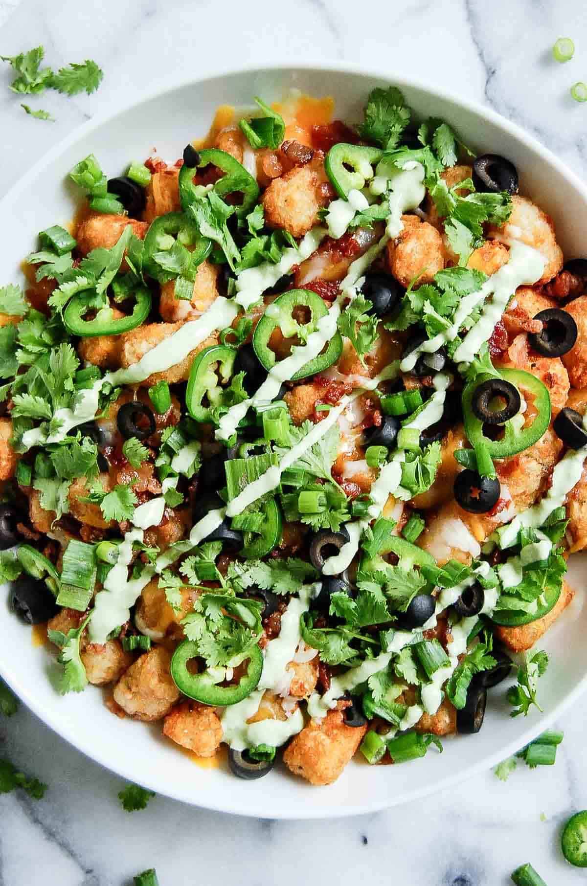 Loaded tater tots in bowl on countertop.
