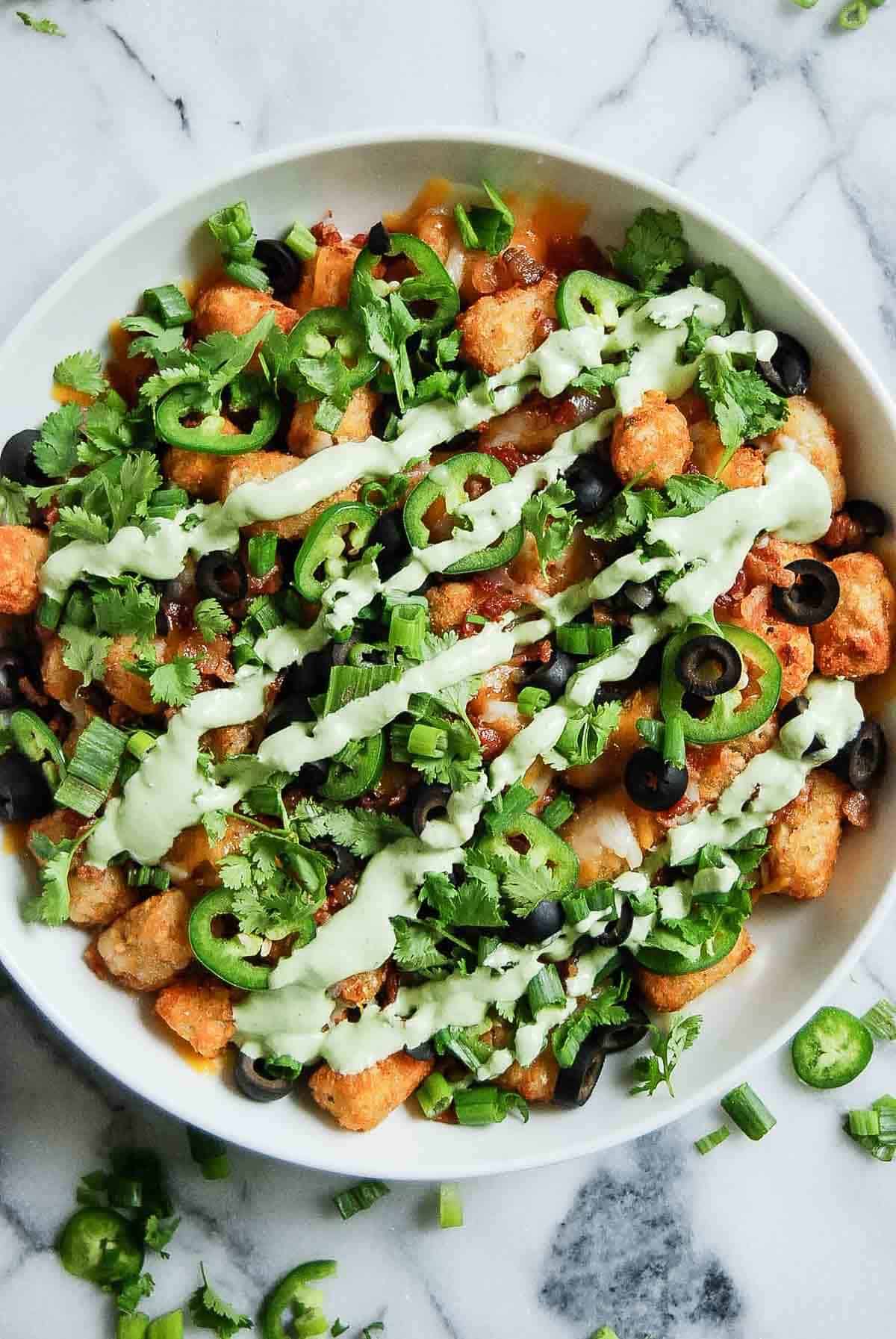 close up of loaded tater tots in bowl on countertop.