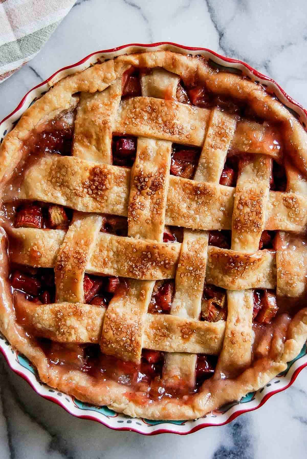 closeup of rhubarb pie with lattice crust on countertop.