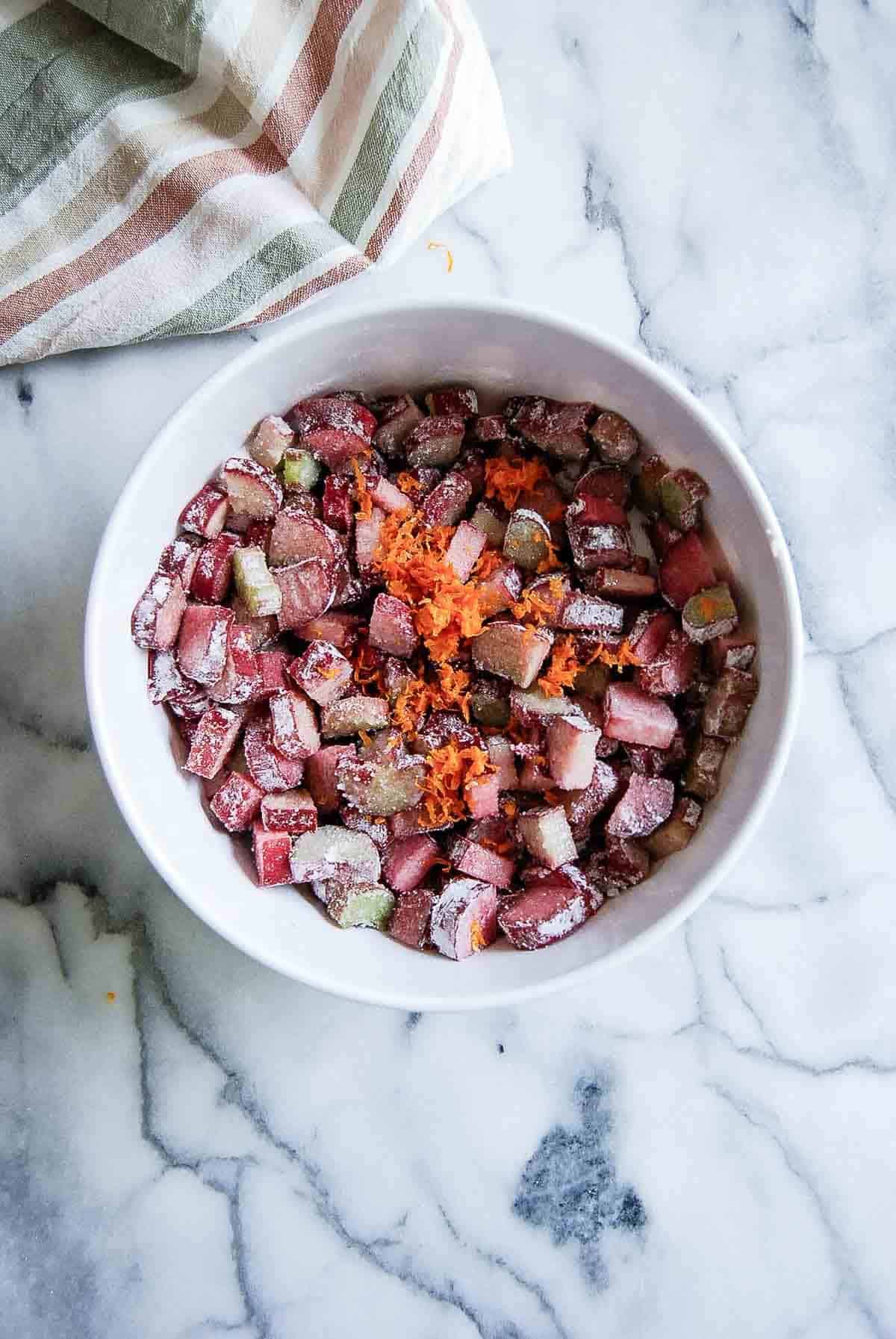 sugar and rhubarb mixture with orange zest in bowl on countertop.