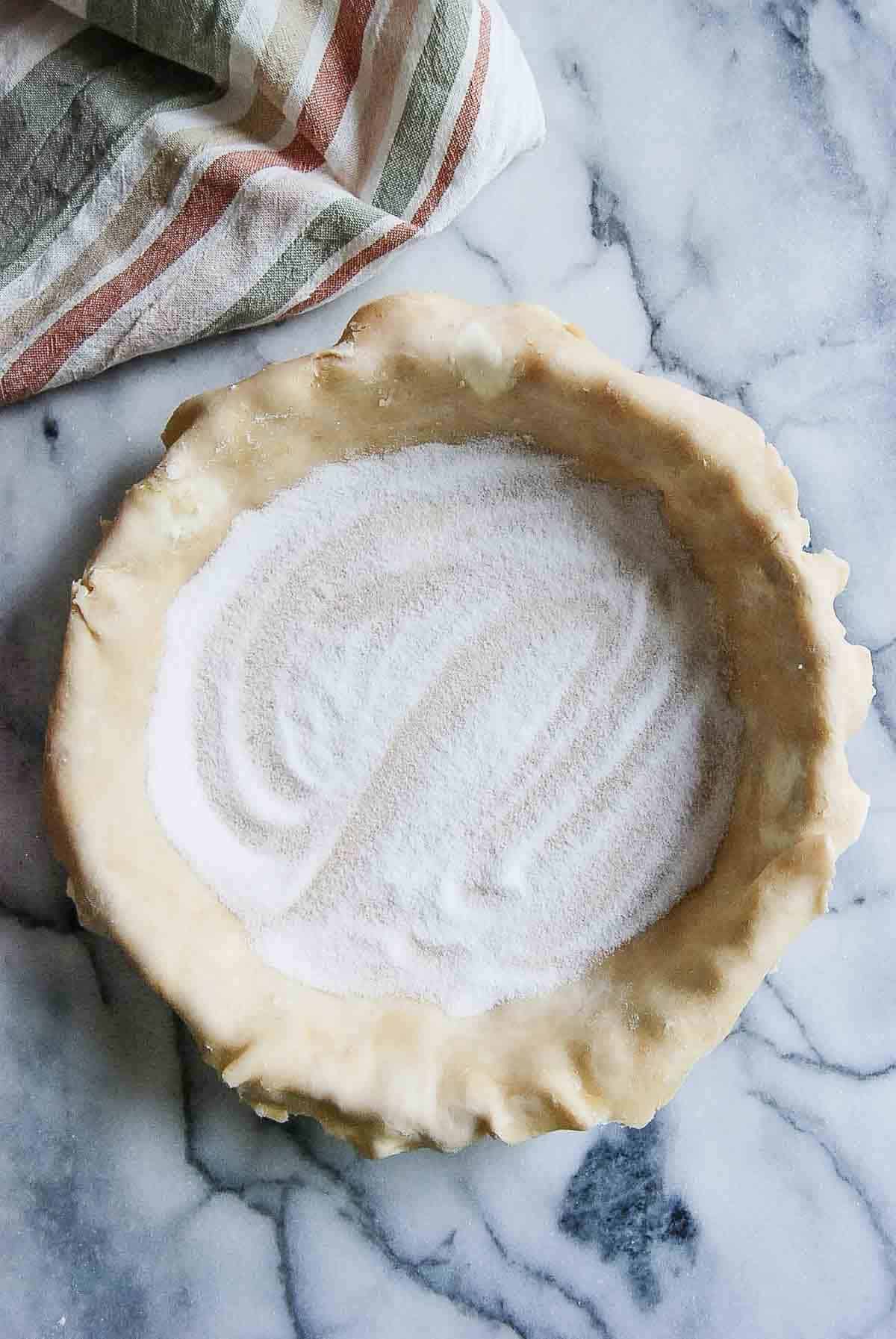 rolled out pie dough in pie plate with sugar spread on the bottom.