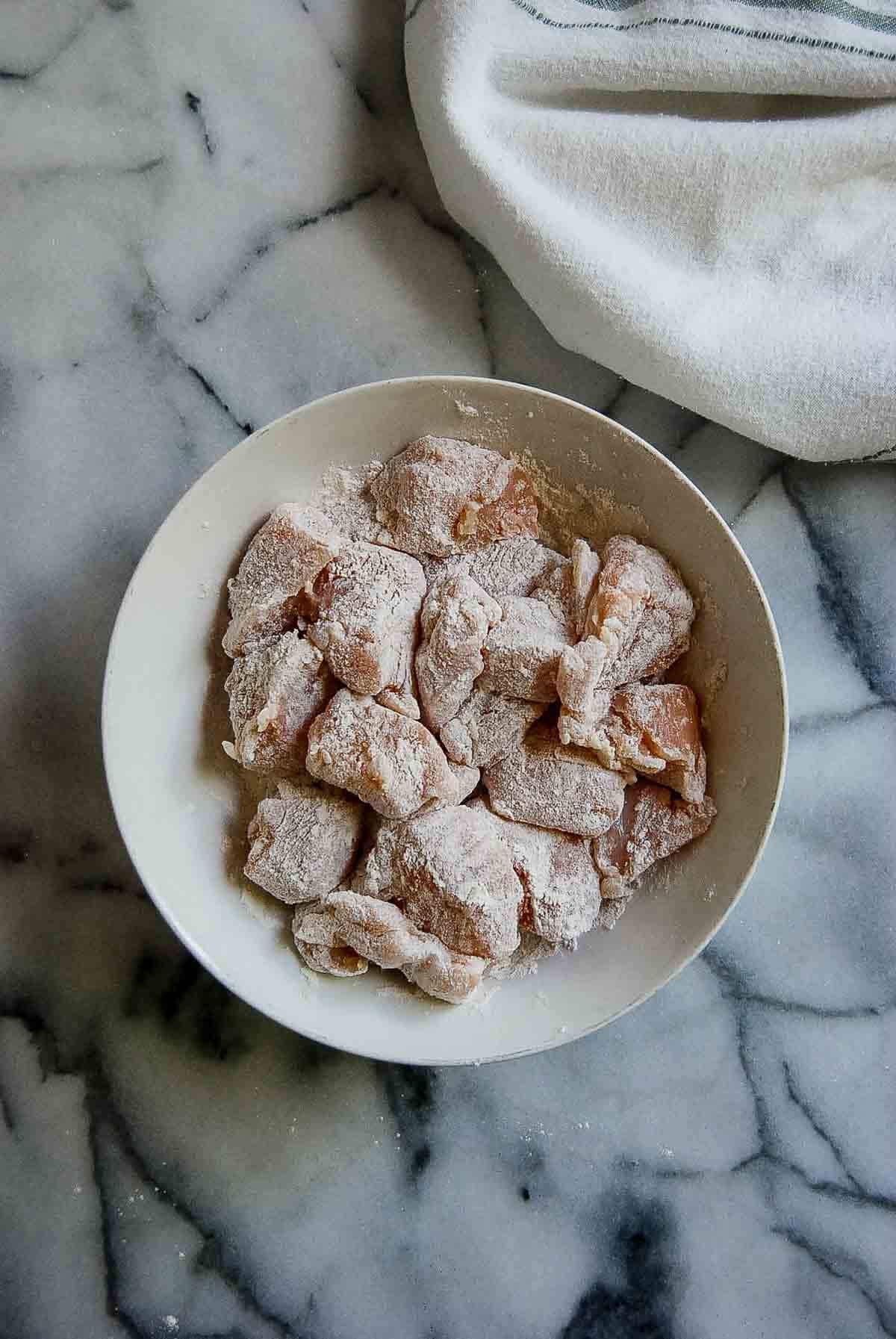 chicken pieces dusted with flour in bowl.