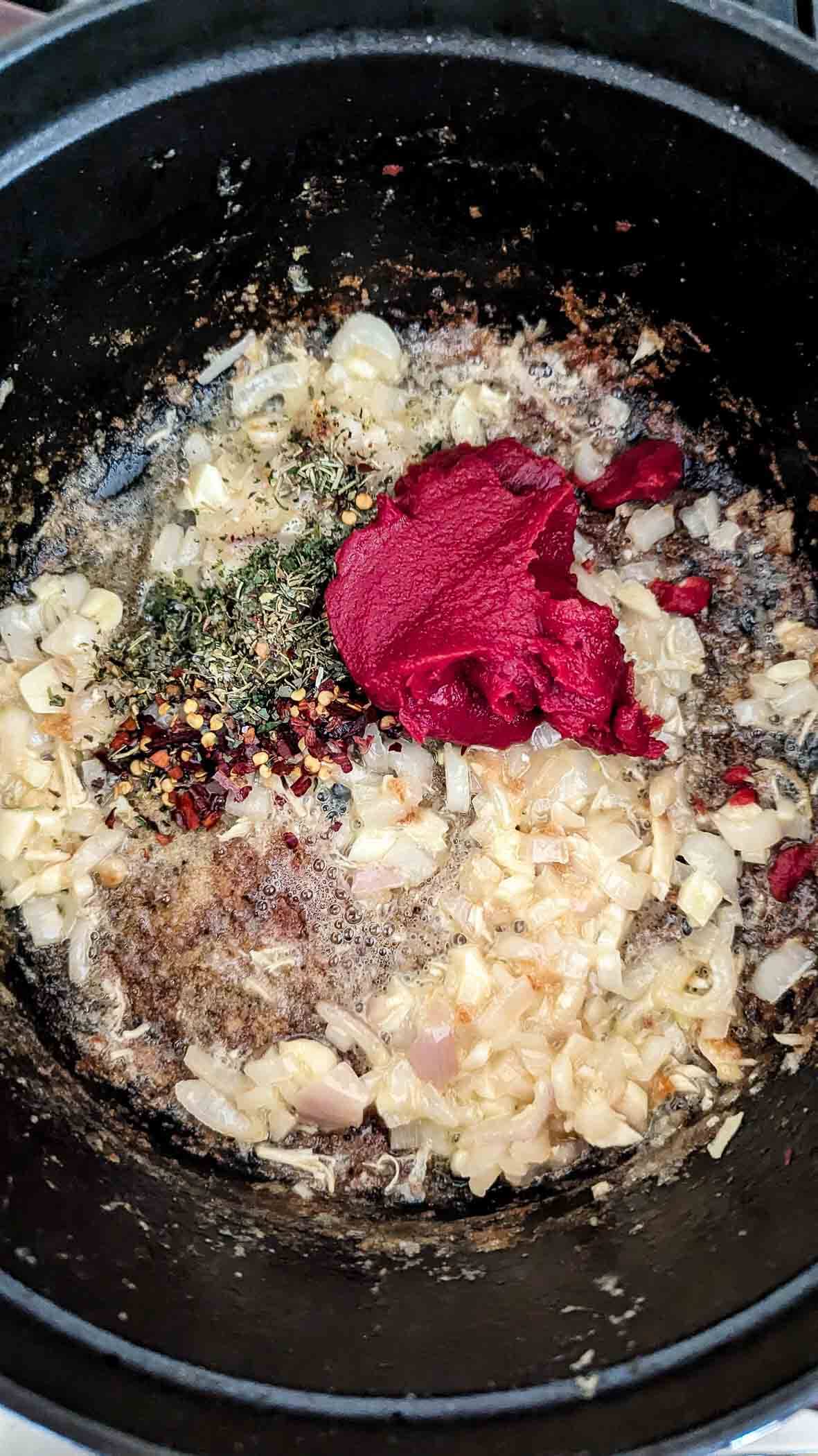 shallots, garlic, spices and tomato paste in pot.