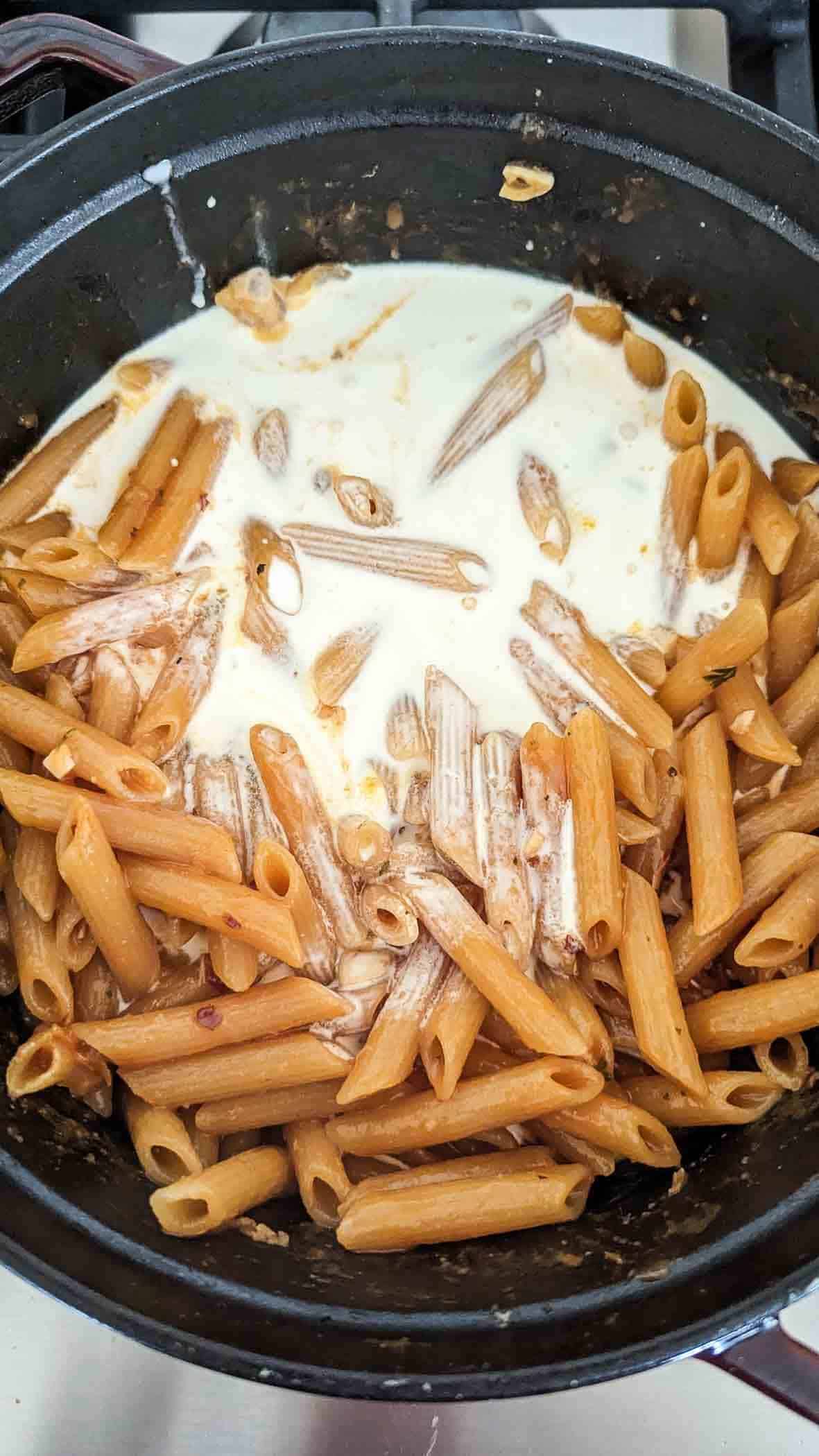 cooked pasta noodles with cream in pot.