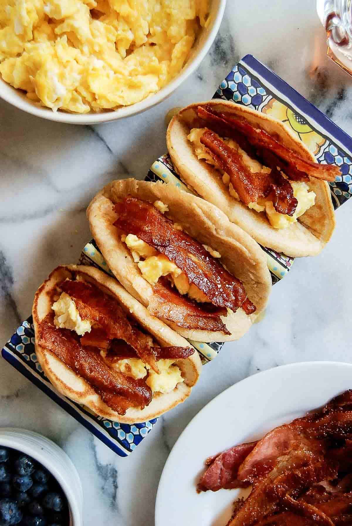 closeup of pancake tacos with bacon and eggs on the countertop.
