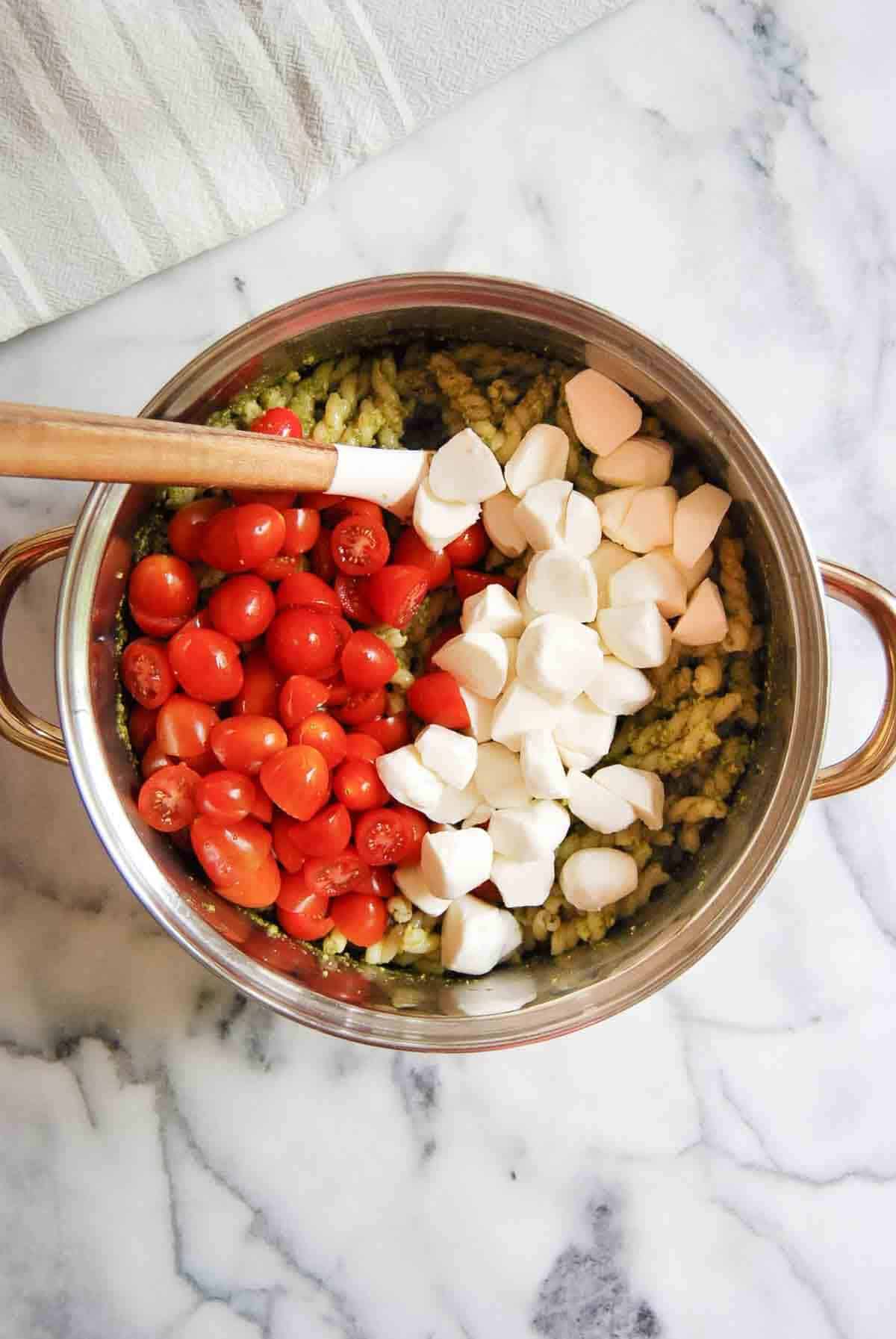 pesto pasta, tomatoes and mozzarella in pot.