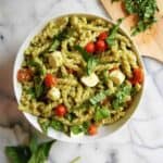 4-ingredient pesto pasta salad in serving bowl on countertop with basil sprinkled on top.