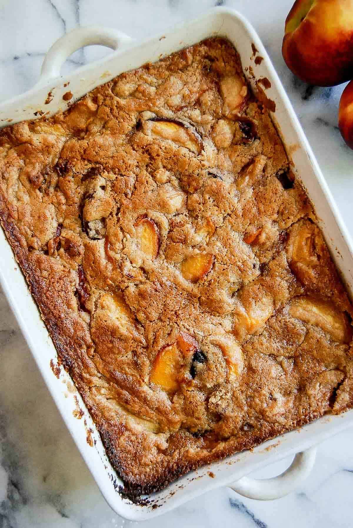 baked peach cobbler (made with cake mix) in casserole dish on countertop.